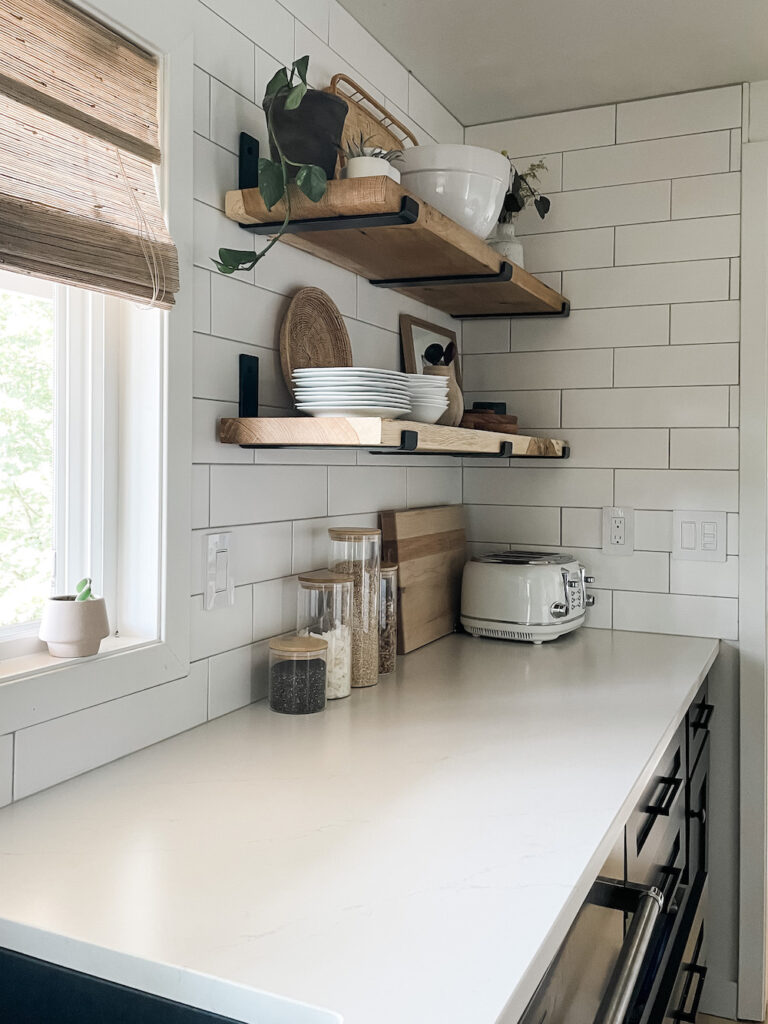 white kitchen countertops with white subway, black cabinets, and open shelving